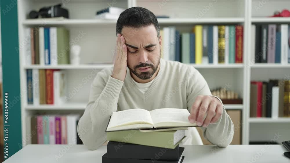 Young hispanic man student sleeping with head on books at library university Young hispanic man student sleeping with head on books at library university