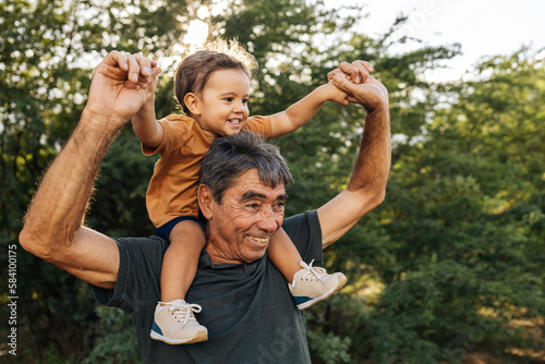 Playful grandfather spending time with his grandson in park on sunny day