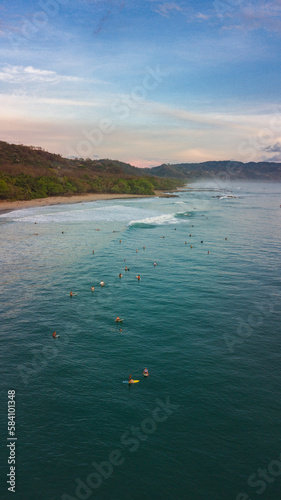 Aerial photography in Costa Rica, surfer enjoying waves and nature during sunset colors