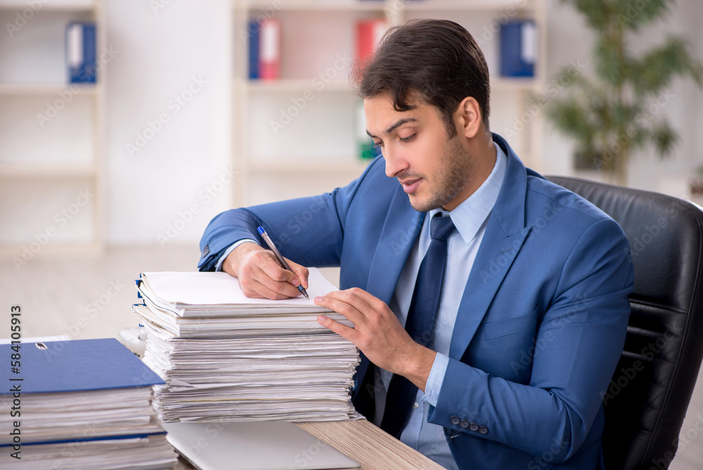 Young male employee and too much work in the office Young male employee and too much work in the office