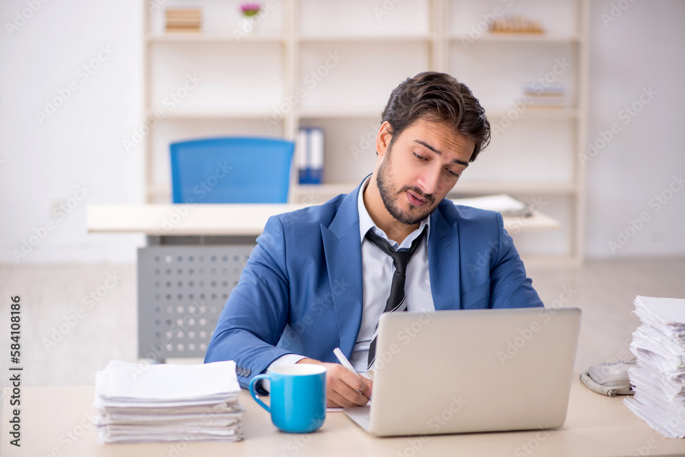 Young male employee and too much work in the office Young male employee and too much work in the office