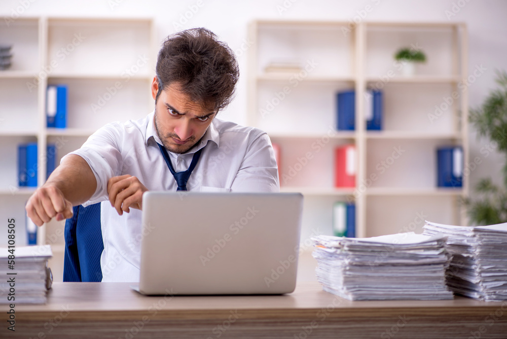 Young male employee and too much work in the office Young male employee and too much work in the office