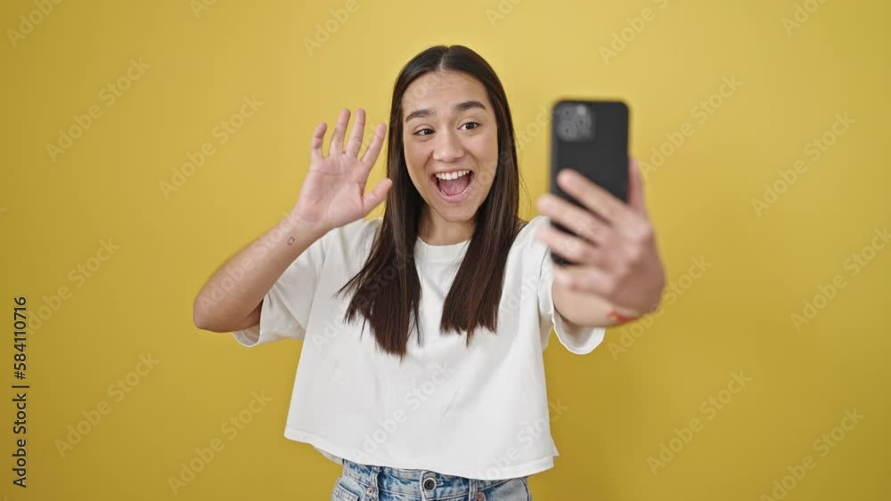 Young beautiful hispanic woman smiling having video call over isolated yellow background Young beautiful hispanic woman smiling having video call over isolated yellow background