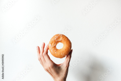 hand holding sweet delicious glazed donut on white background.
