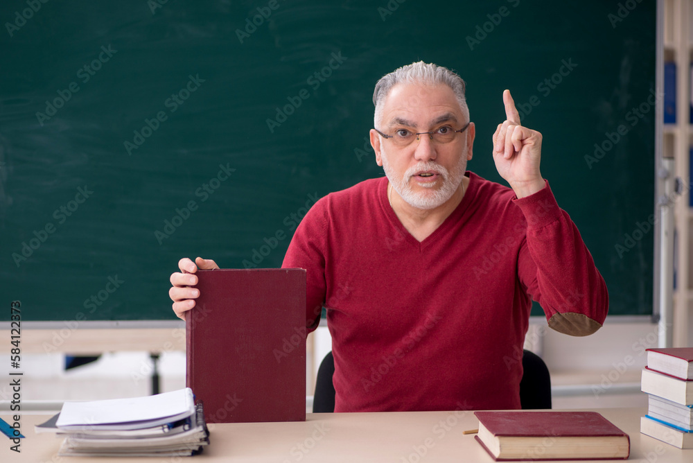 Old male teacher sitting in the classroom Old male teacher sitting in the classroom