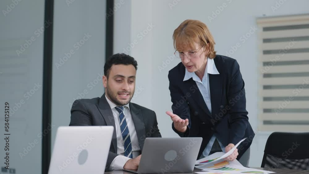 Indian businessman and businesswoman manager talking and brainstorm using laptop shares sales growth of company in meeting room at modern office 