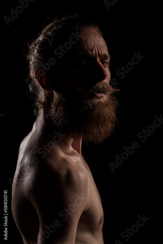Portrait of bearded guy on black background in studio photo. Expression and fashion