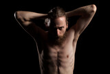 Cool looking bearded man in deep shadows and black background in studio photo