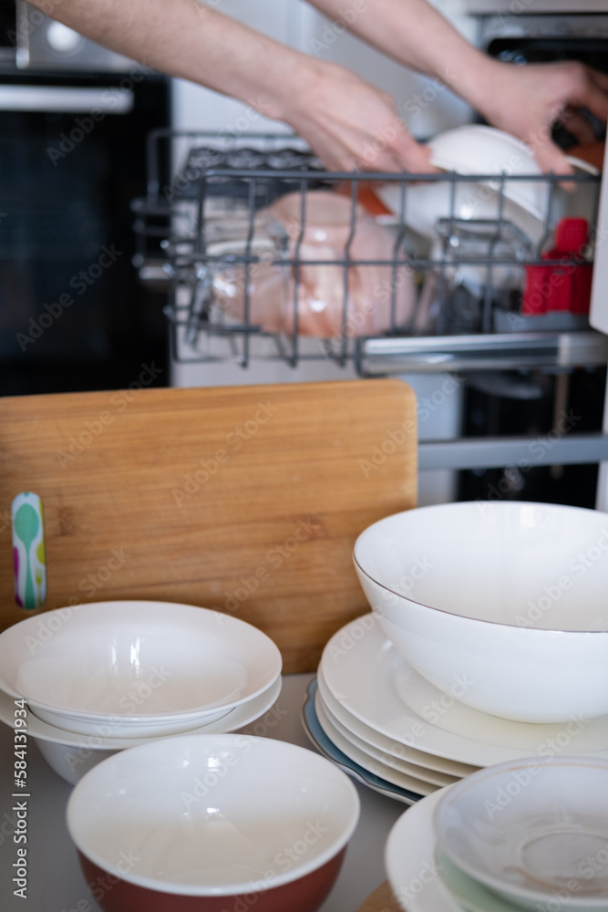 Women's hands sort clean dishes from the dishwasher Women's hands sort clean dishes from the dishwasher