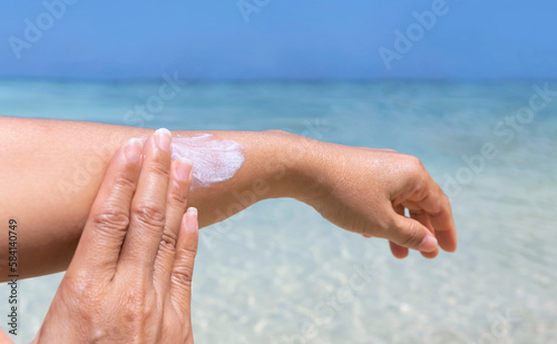 Woman hand with sunscreen cream on the sand beach as applying moisturizing lotion on .Skin care protection concept