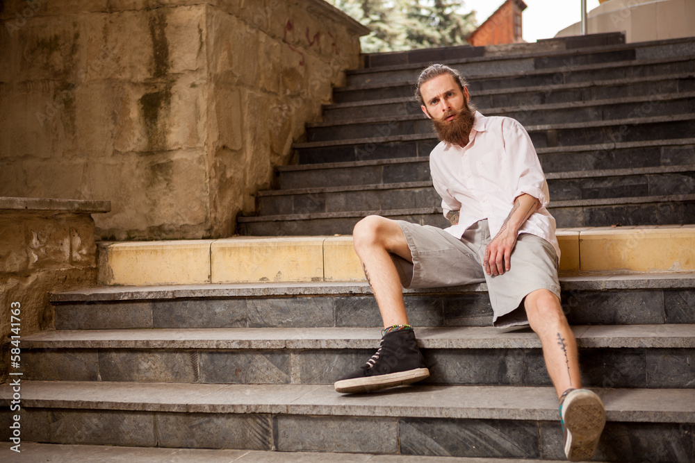 Tattoed and bearded hipster guy posing outdoor in the city