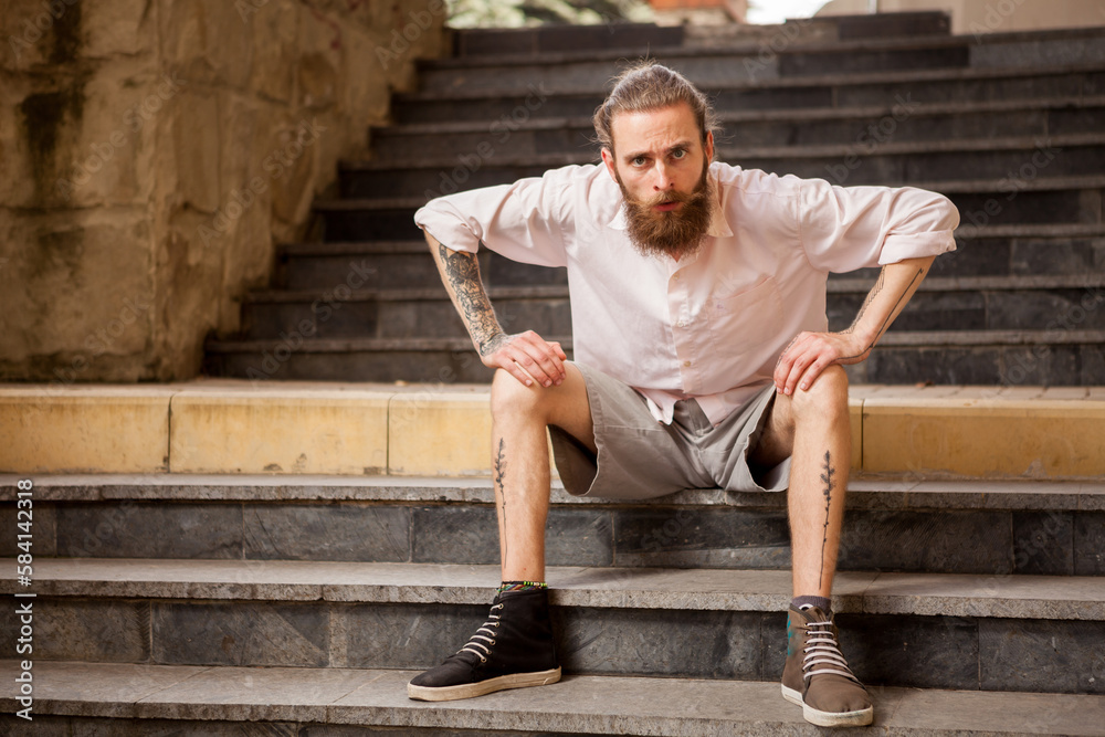 Tattoed and bearded hipster guy posing outdoor in the city