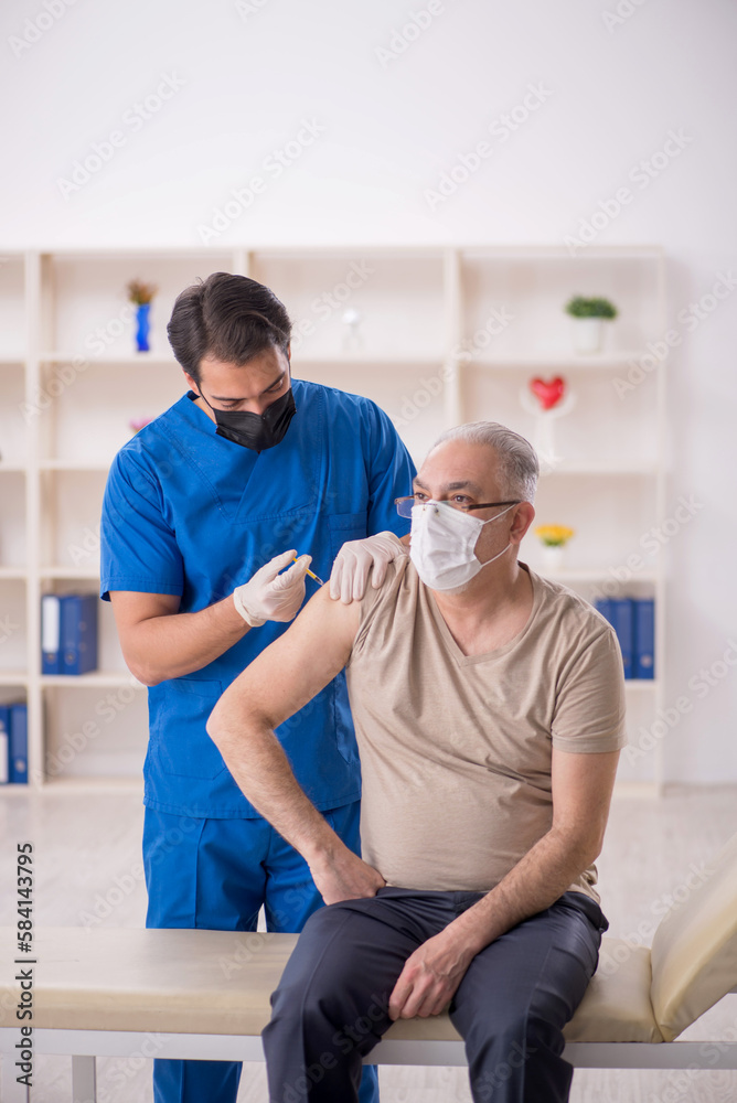 Old male patient visiting young male doctor in vaccination conce Old male patient visiting young male doctor in vaccination conce