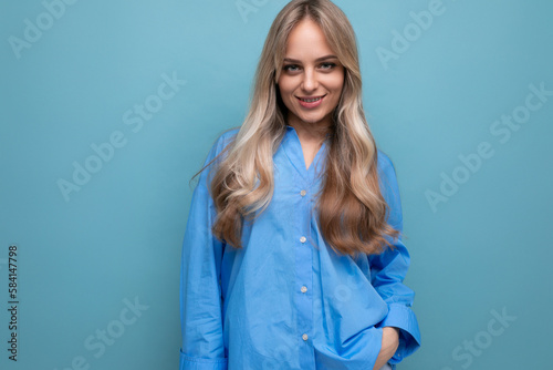 cheerful blond girl in a blue shirt isolated on a blue background
