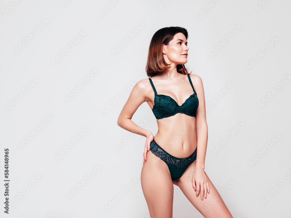 Young beautiful sexy woman in green lace lingerie. Smiling carefree confident model wearing green underwear. Hot brunette posing on white wall in studio. Perfect body. Slim and fit. Isolated Young beautiful sexy woman in green lace lingerie. Smiling carefree confident model wearing green underwear. Hot brunette posing on white wall in studio. Perfect body. Slim and fit. Isolated