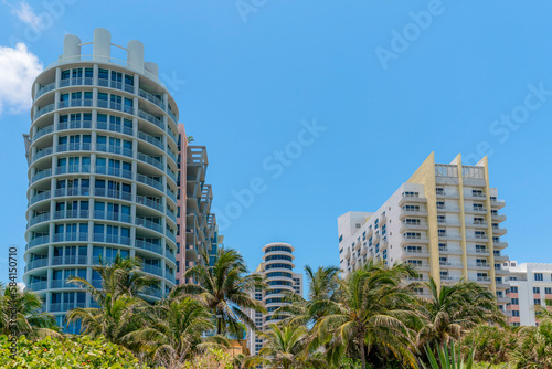 Modern hotels apartments with balconies against the blue skies in Miami, Florida. There are buildings on the left with round walls near the building on the right with yellow trims. © Jason
