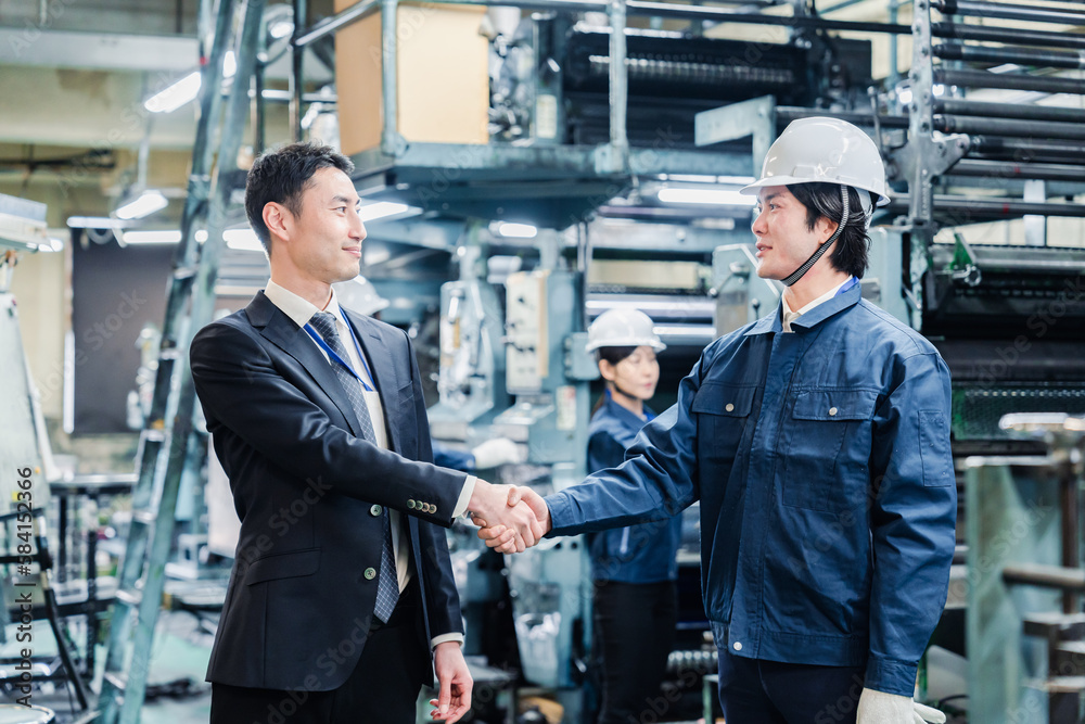 取引先と握手をする工場のスタッフ 取引先と握手をする工場のスタッフ