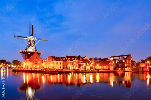 Holland Traveling. Night City View of Harlem With De Adriaan Windmill on Spaarne River On The Background During Blue Hour.