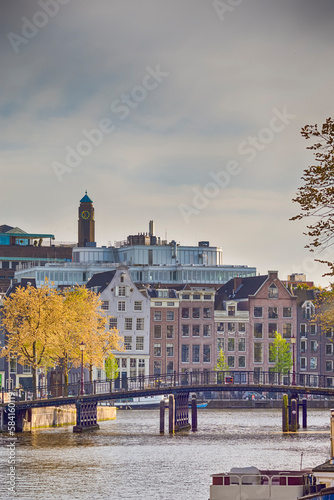 Traveling in Netherlands. Amsterdam Cityscape With Arched Bridge For Canal Boat Cruises And Traditional Dutch Houses