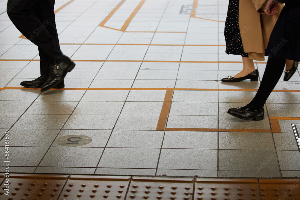 駅のホームで歩く人々の足元の姿 駅のホームで歩く人々の足元の姿