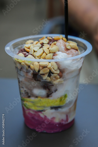 Ice cream podeng in a plastic cup with nuts on a black background. photo