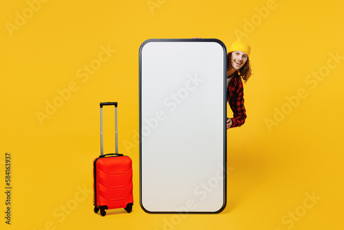 Traveler fun man wear casual clothes stand near big huge blank screen mobile cell phone bag suitcase isolated on plain yellow background studio. Tourist travel abroad in free spare time rest getaway. #584163937