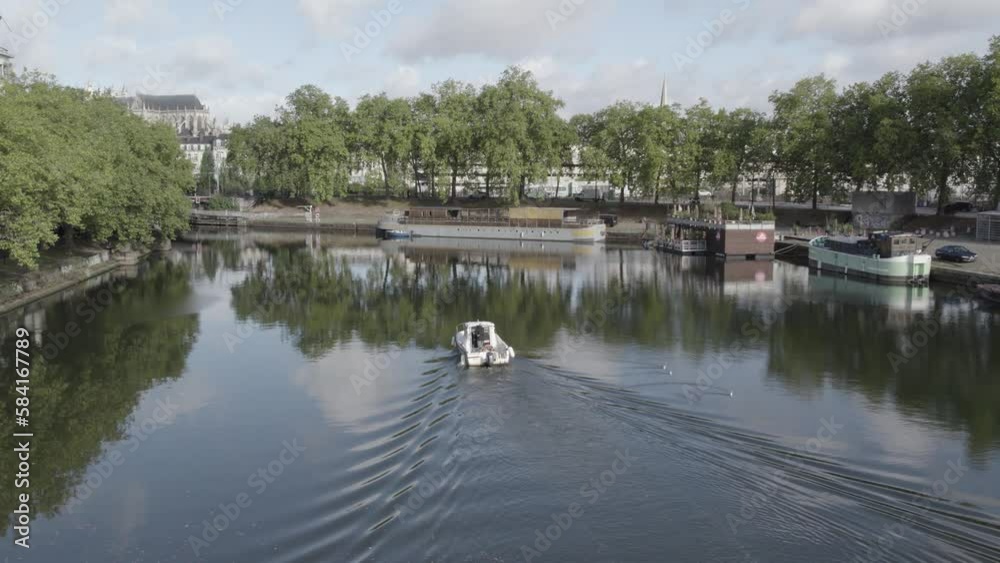 Small motorboat traversing the River Erdre on the city on Nantes in Western France, Aerial following behind shot Small motorboat traversing the River Erdre on the city on Nantes in Western France, Aerial following behind shot