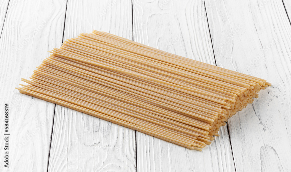 Uncooked spaghetti pasta on white wooden background