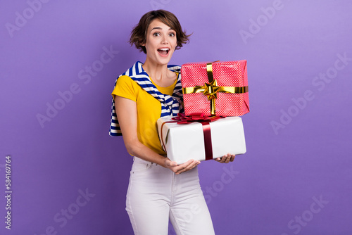 Photo of joyful cheerful astonished lady wear trendy striped yellow clothes share gifts holiday event isolated on purple color background