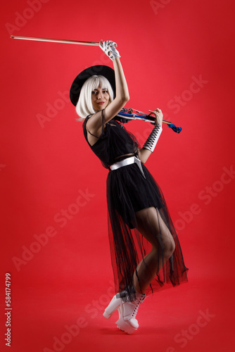 Violinist woman in the stage costume on the red background.
