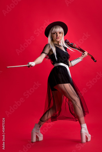 Violinist woman in the stage costume on the red background.