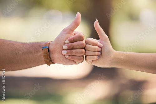 Thumbs up, fist bump and people with outdoor teamwork, support and collaboration mission or agreement. Man, woman partner or couple of friends with like, deal and success hands sign, power and park © Sharne T/peopleimages.com