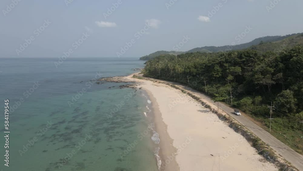 White truck drives on paved road by sand beach on Koh Lanta, Thailand
