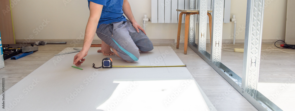 A man makes repairs in the room. Installing an interior wall. Pano.