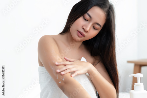 Body skincare treatment concept. woman applying skin cream arm area sittin in dressing room. Body care pampering, beauty routine.