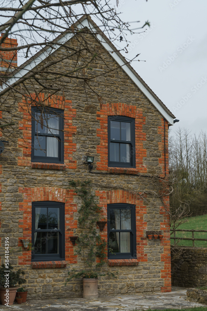 Naklejka premium Home Exterior in United Kingdom. Old farmhouse exterior image. Located in England in the Somerset countryside. Contemporary doors and windows in traditional farm house building.