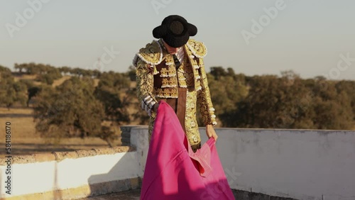 Bullfighter dressed in traditional costume of lights practicing with a cape on a terrace overlooking the countryside