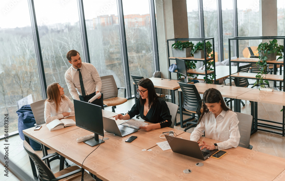 Sitting by the table. Business people in formal clothes are working in the office together Sitting by the table. Business people in formal clothes are working in the office together