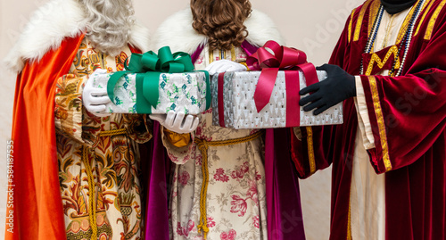 Melchor, Gaspar y Baltasar, Los tres Reyes Magos sujetando dos regalos en fondo claro photo