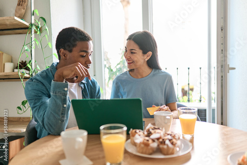 Multiethnic couple shopping online using a laptop and credit card