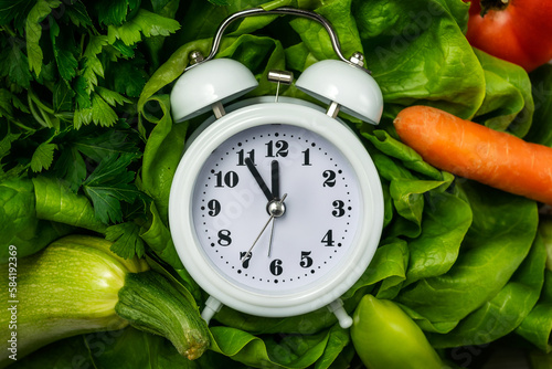 Diet time. Food clock. Healthy food concept with vegetables on wooden table photo