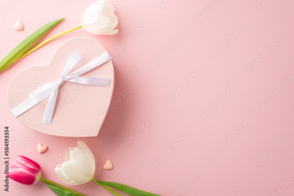 Mother's Day concept. Top view photo of heart shaped giftbox with ribbon bow pink and white tulips on isolated pastel pink background with copyspace
