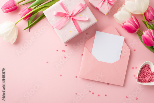Mother's Day concept. Top view photo of gift boxes bunches of pink and white tulips open envelope with letter and heart shaped saucer with sprinkles on isolated pastel pink background with copyspace © ActionGP