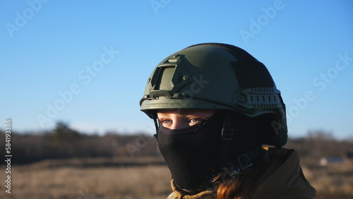 Dolly shot of ukrainian army woman in helmet and balaclava looking at sunset. Female military woman standing against background of blue sky. Victory against russian aggression. Concept of end of war