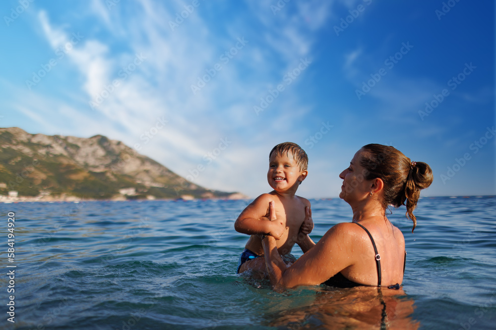 Cheerful mother plays with her son in the sea Cheerful mother plays with her son in the sea