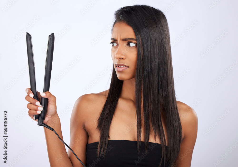 Angry, woman or hair straightener for beauty self care or treatment in studio on white background. Unhappy, frustrated Indian girl model or salon equipment for ironing in grooming routine for styling Angry, woman or hair straightener for beauty self care or treatment in studio on white background. Unhappy, frustrated Indian girl model or salon equipment for ironing in grooming routine for styling