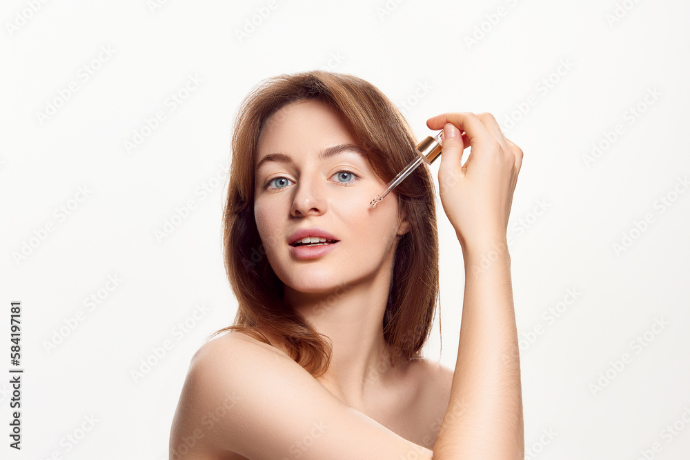 Beautiful with healthy, spotless, clear skin applying face serum, taking care after skin condition against white background. Skin care, cosmetology, cosmetics, natural beauty, plastic surgery concept Beautiful with healthy, spotless, clear skin applying face serum, taking care after skin condition against white background. Skin care, cosmetology, cosmetics, natural beauty, plastic surgery concept