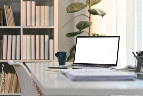 White working desk in modern home office with laptop computer, coffee cup and documents. Blank screen for advertising design © Prathankarnpap