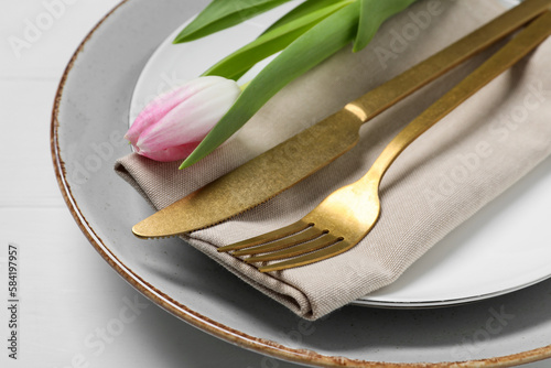 Stylish table setting with cutlery and tulip on white wooden background