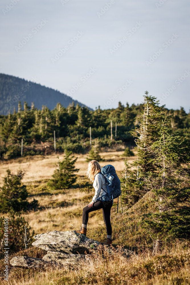 Woman hiking in mountains. Tourist with backpack walks on trekking trail. Adventure in nature